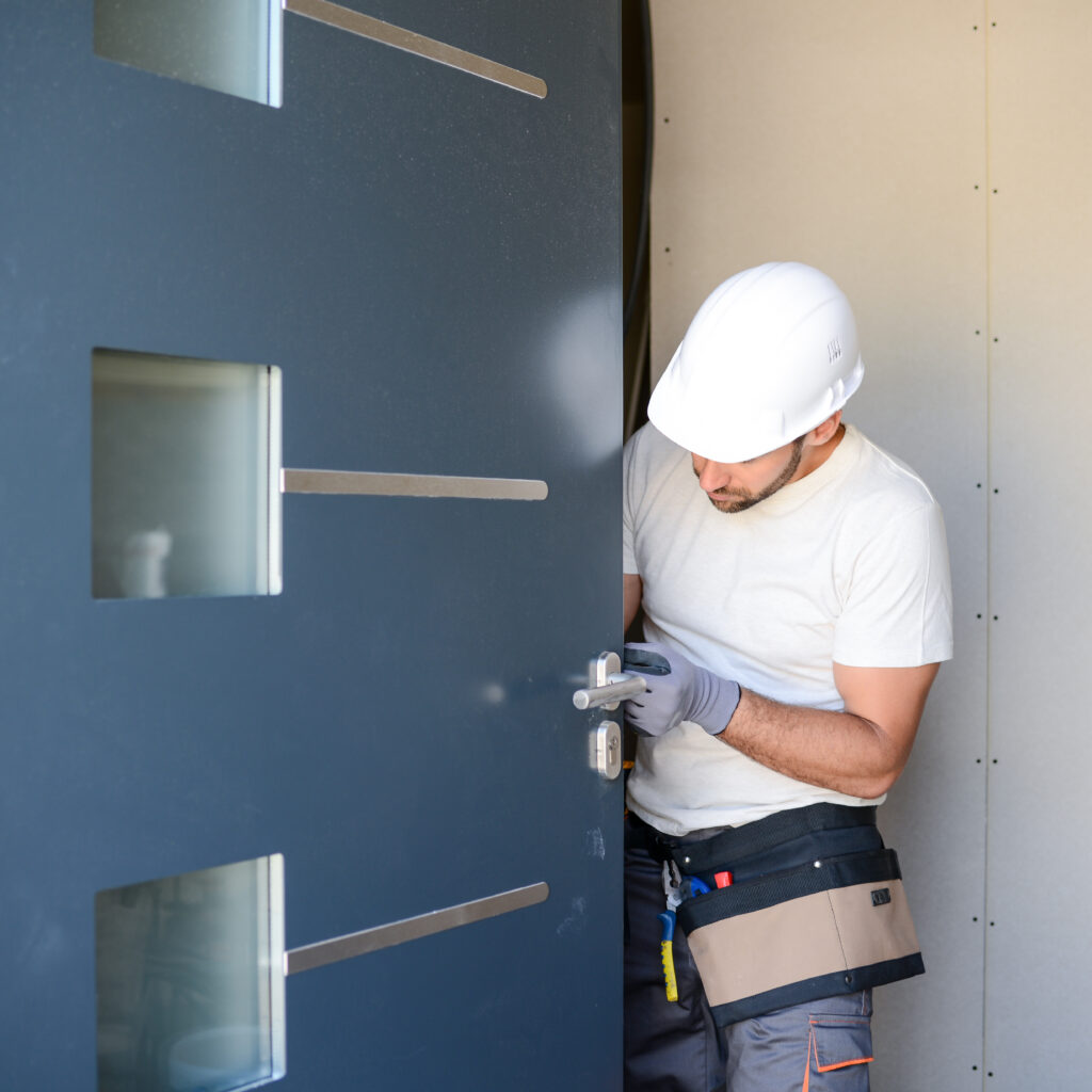 handsome young man installing door in a new house construction site